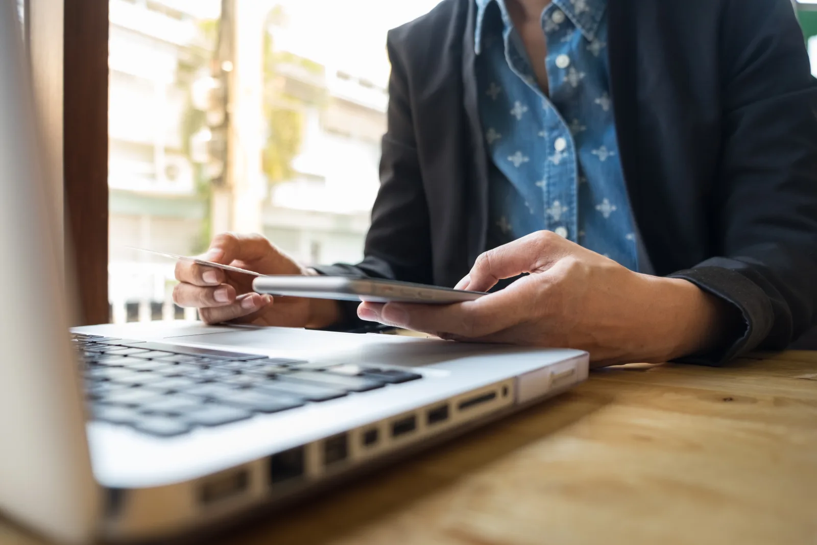 Persona utiliza una tarjeta y una tableta junto a una computadora